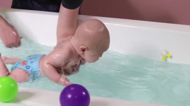 Un padre ayuda es niño durante las clases de natación en la piscina . — Vídeos de Stock