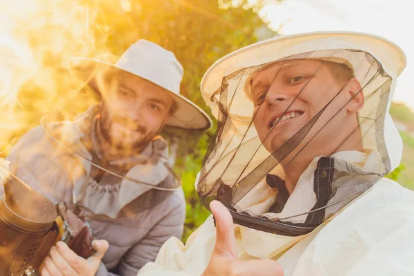 Experienced beekeeper grandfather teaches his grandson caring for bees. Apiculture. The concept of transfer of experience.