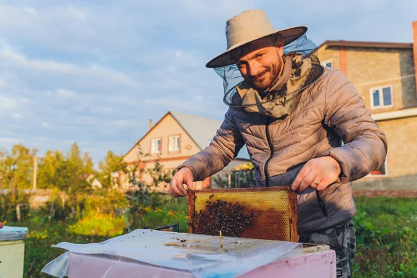 De ervaren grootvader van de imker leert zijn kleinzoon voor bijen te zorgen. Bijenteelt. Het begrip overdracht van ervaring. — Stockfoto