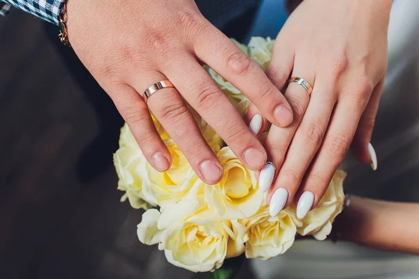 Close-up. Hand of bride and groom. Bride and groom hold hands. Focus on the rings. Bouquet in hand. — Stock Photo, Image