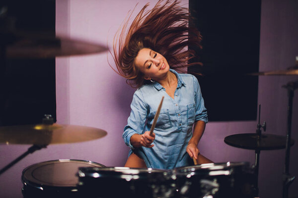 Photograph of a female drummer playing a drum set on stage.