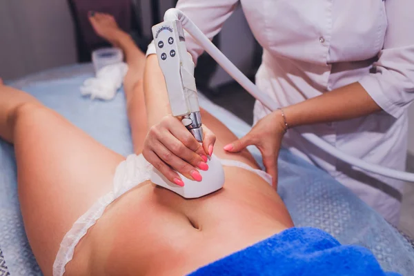 Vista recortada del cosmetólogo con rodillo haciendo masajes de inanición en las nalgas . —  Fotos de Stock