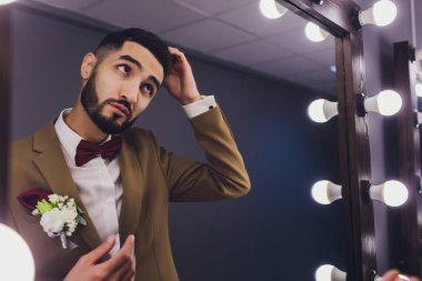 Yakışıklı güçlü şık sakallı damat ayna yakınında poz.