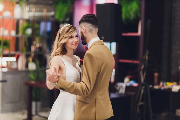 Stylish happy bride and groom posing at big love word in evening light at wedding reception outdoors. Gorgeous wedding couple of newlyweds having fun in evening park. — Stock Photo, Image