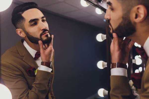 Guapo fuerte con estilo barbudo novio posando cerca del espejo . — Foto de Stock