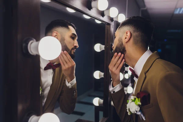 Гарний міцний стильний бородатий наречений позує біля дзеркала . — стокове фото