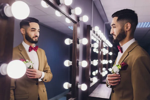 Bello forte elegante barbuto sposo posa vicino specchio . — Foto Stock