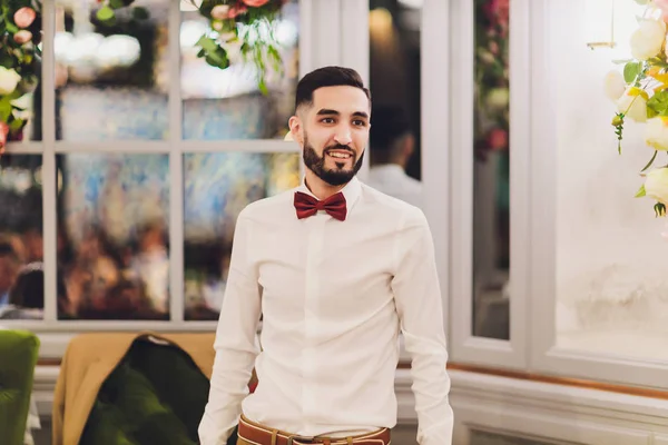 Feliz novio barbudo guapo en traje con un restaurante en el fondo . — Foto de Stock