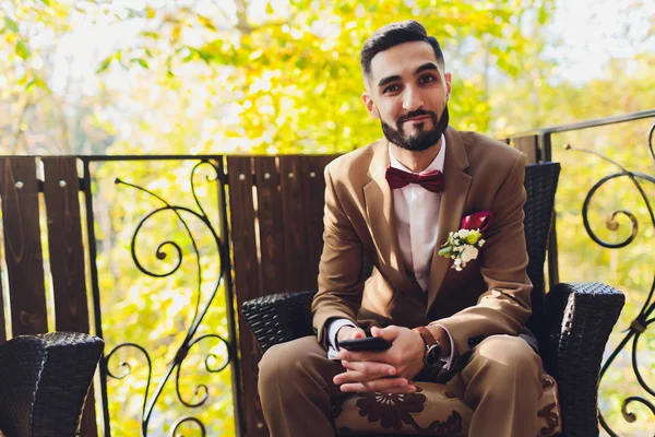Feliz novio barbudo guapo en traje con un restaurante en el fondo . —  Fotos de Stock