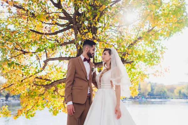 Noiva feliz elegante e noivo posando na palavra de amor grande na luz da tarde na recepção de casamento ao ar livre. Casal lindo casal de recém-casados se divertindo no parque da noite . — Fotografia de Stock