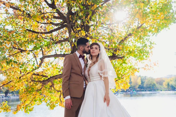 Noiva feliz elegante e noivo posando na palavra de amor grande na luz da tarde na recepção de casamento ao ar livre. Casal lindo casal de recém-casados se divertindo no parque da noite . — Fotografia de Stock