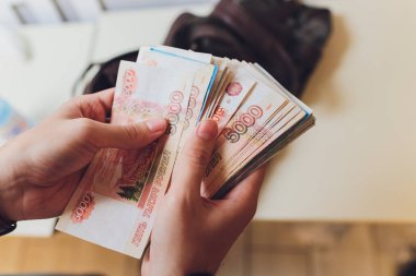 Gri arka plan elinde para dolu bir evrak çantası ile işadamı.