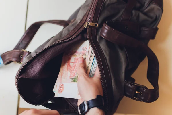 Empresario con un maletín lleno de dinero en las manos de sobre fondo gris . — Foto de Stock