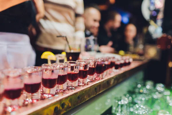 Barman derramando bebida alcoólica forte em pequenos copos no bar, tiros . — Fotografia de Stock
