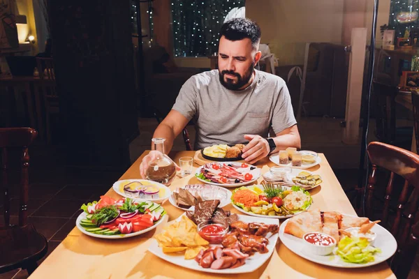 Человек пьет водку за большим столом с едой и закусками . — стоковое фото