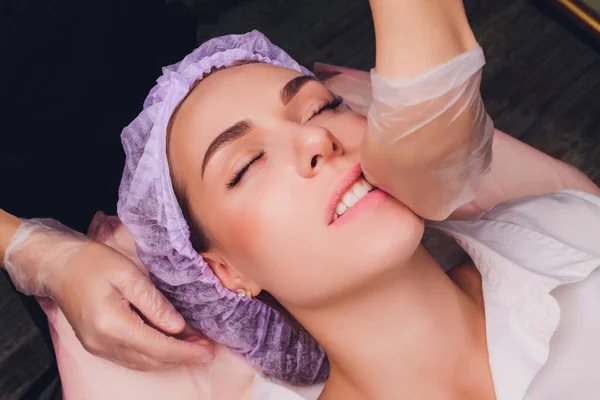 Schoonheidsspecialist maakt een buccale massage van de patiënten gezichtsspieren. — Stockfoto