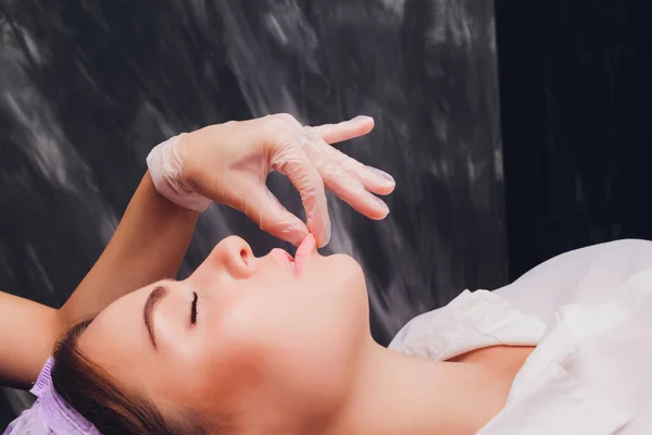 Kosmetolog sprawia, że masaż policzkowy pacjentów mięśnie twarzy. — Zdjęcie stockowe