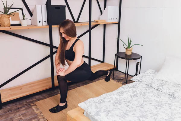 Atractivo fitness mujer haciendo ejercicios de estiramiento en casa, como parte de un estilo de vida saludable sin ir al gimnasio . — Foto de Stock