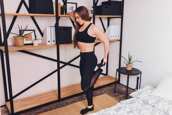 Çekici fitness kadını spor salonuna gitmeden sağlıklı bir yaşam tarzının bir parçası olarak evde esneme egzersizleri yapıyor.. — Stok fotoğraf