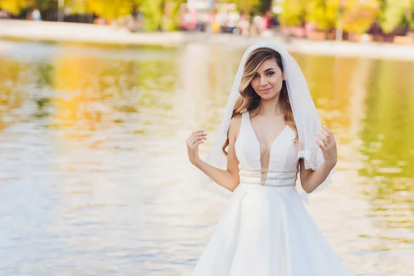 Mariée posant dans un parc vert fille dans une robe blanche sur un fond de vert . — Photo