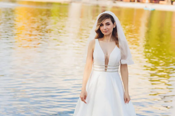 Mariée posant dans un parc vert fille dans une robe blanche sur un fond de vert . — Photo