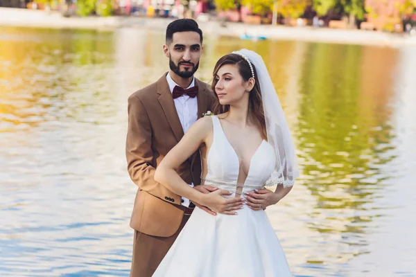 Mariée et marié heureux élégant posant au grand mot d'amour dans la lumière du soir à la réception de mariage en plein air. Superbe couple de mariage de jeunes mariés s'amusant dans le parc du soir . — Photo