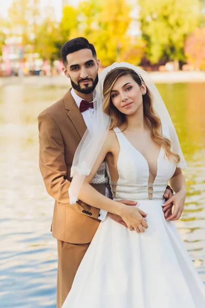 Noiva feliz elegante e noivo posando na palavra de amor grande na luz da tarde na recepção de casamento ao ar livre. Casal lindo casal de recém-casados se divertindo no parque da noite . — Fotografia de Stock