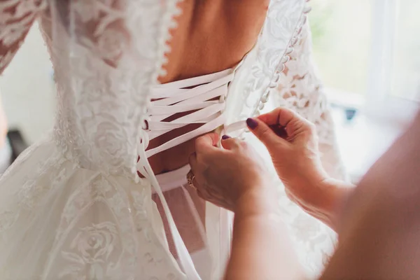 A abotoar o vestido na noiva. Detalhes de belo vestido de noiva de renda . — Fotografia de Stock