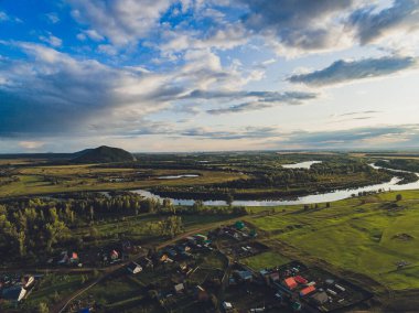 Shihan Yuraktau 'nun eteklerindeki yulaf tarlası ve köy. Bashkortostan Cumhuriyeti. Rusya.