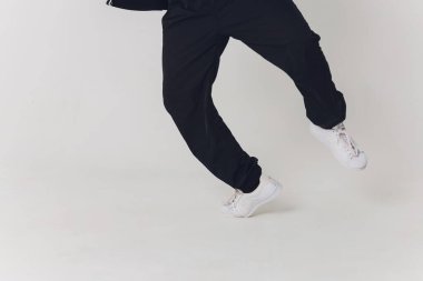 Yakından, siyah pantolon giymiş yakışıklı genç dansçı, çıplak bir gövdede bir kazak kaldırıyor bir bacağını sokak dansı yaparken kaldırıyor..