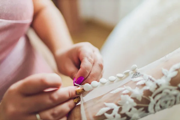 A abotoar o vestido na noiva. Detalhes de belo vestido de noiva de renda . — Fotografia de Stock