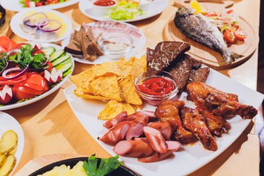 Çeşitli abur cubur ve salatalarla dolu yemek masası. Somon, zeytin, şarap, sebze, ızgara balık tostu. Aile yemeği konsepti. Şükran Günü, Noel. Üst veiw.