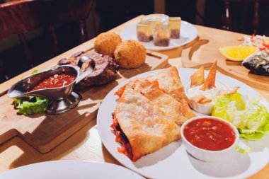 Çeşitli abur cubur ve salatalarla dolu yemek masası. Somon, zeytin, şarap, sebze, ızgara balık tostu. Aile yemeği konsepti. Şükran Günü, Noel. Üst veiw.