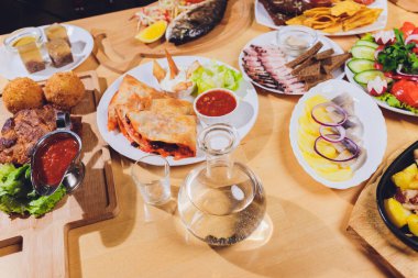 Çeşitli abur cubur ve salatalarla dolu yemek masası. Somon, zeytin, şarap, sebze, ızgara balık tostu. Aile yemeği konsepti. Şükran Günü, Noel. Üst veiw.