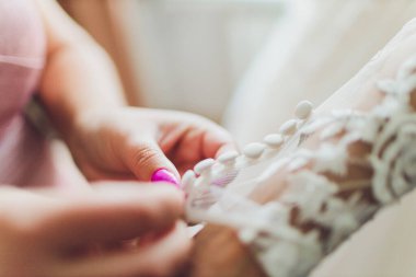 Gelinin düğmelerini ilikliyorum. Güzel dantelli gelinliğin ayrıntıları.