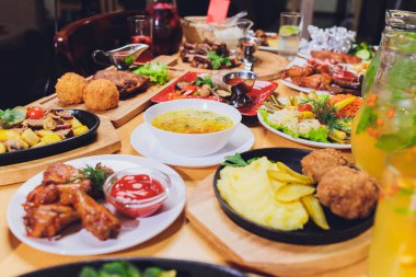 Yemek masası ile et ızgara, kızartma yeni patates, sebze, salata, soslar, aperatifler ve limonata, üstten görünüm.