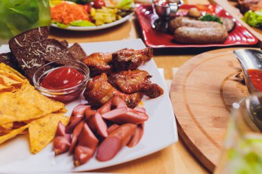 Yemek masası ile et ızgara, kızartma yeni patates, sebze, salata, soslar, aperatifler ve limonata, üstten görünüm.