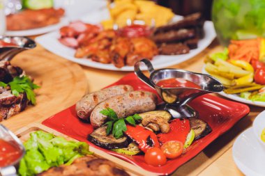 Akşam yemeği parti gıda kavramı. Izgara sosis ile yemek masası, tortilla saran, bira içmek ve ahşap masa, rustik tarzı üzerinde farklı yemekler.