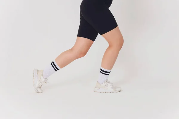 Nahaufnahme, hübsche junge Tänzerin in schwarzer Hose, Sweatshirt auf nacktem Oberkörper hebt ein Bein beim Streetdance. — Stockfoto