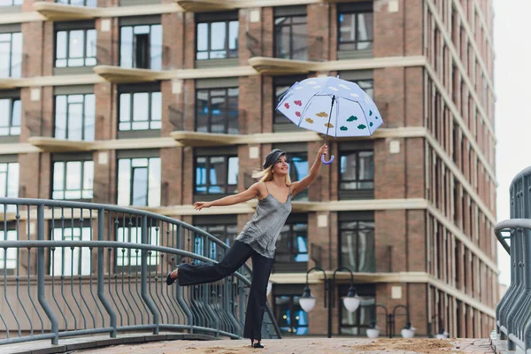 Dívka s deštníkem pobíhající po ulici v deštivém dni. — Stock fotografie