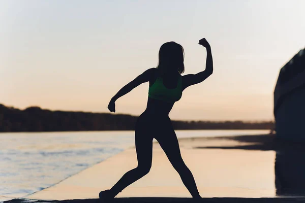 Silhueta de uma menina que dança em um campo em um fundo por do sol . — Fotografia de Stock