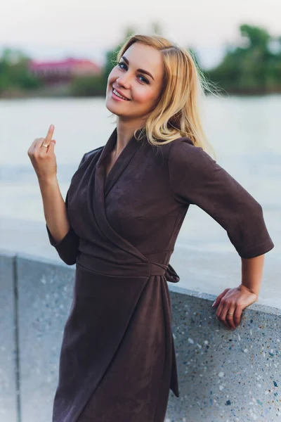 Retrato al aire libre de la joven hermosa mujer caucásica con el pelo largo y recto en vestido corto negro, zapatos beige sosteniendo bolso de cuero marrón caminando calle de la ciudad . — Foto de Stock