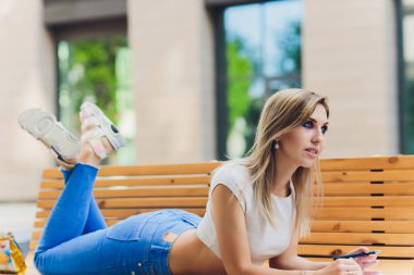 Kız bir deftere yazıyor, parkta bir bankta oturuyor..