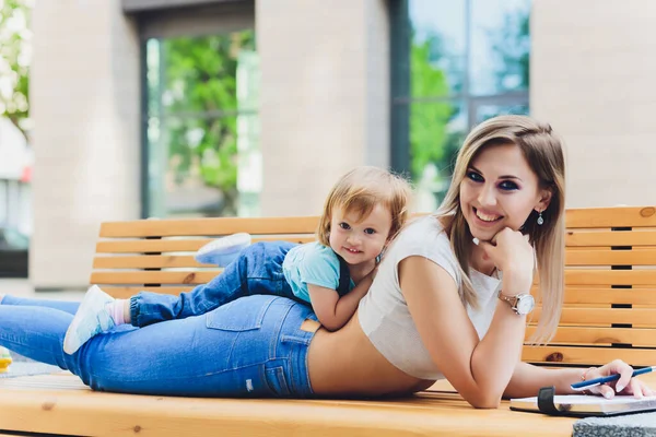 Moeder en dochter op een bankje las een boek in het park, het concept van familierelaties, en familie waarden. — Stockfoto