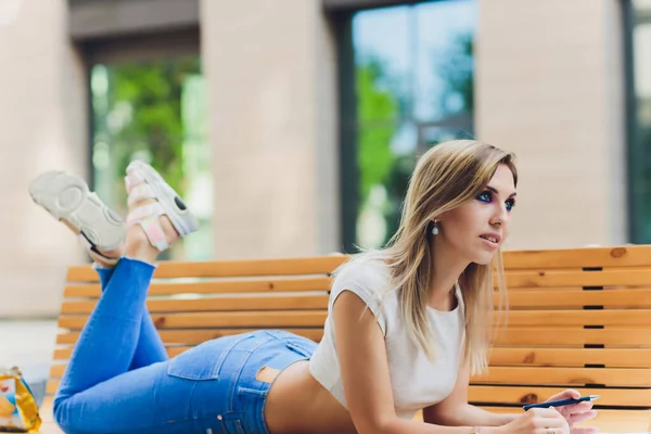 Mädchen schreibt in ein Notizbuch, sitzt auf einer Bank im Park. — Stockfoto