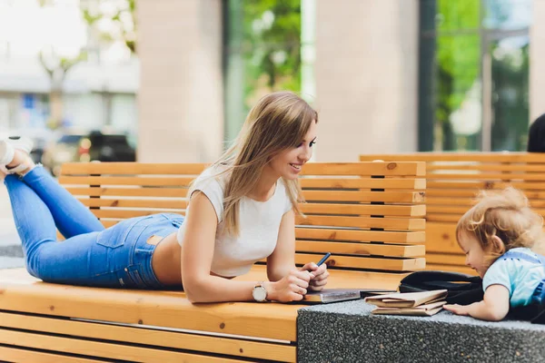 Moeder en dochter op een bankje las een boek in het park, het concept van familierelaties, en familie waarden. — Stockfoto