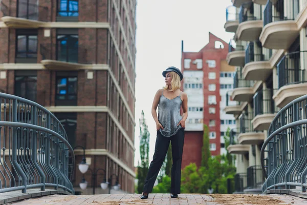 Blond meisje dragen op jeans met rugzak poseerde tegen modern huis. — Stockfoto