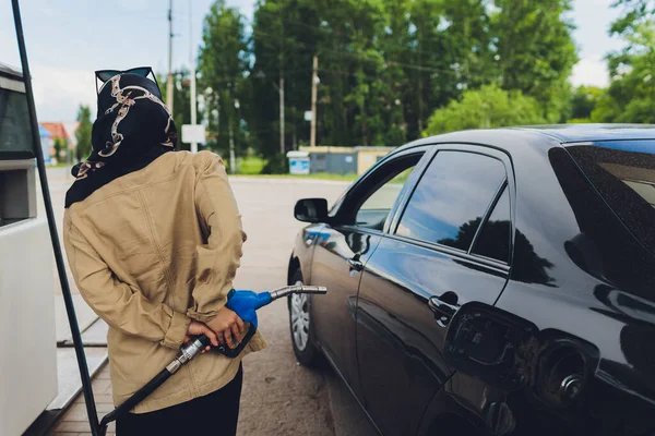 Tailandês muçulmano mulher trabalhador usando hijab combustível de enchimento para um carro com pistola de gasolina no posto de gasolina . — Fotografia de Stock