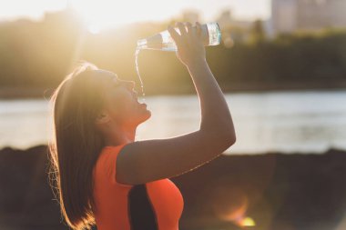 Eğitimden sonra su içen zayıf genç bir kadın..