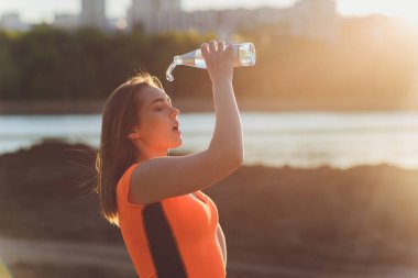 Eğitimden sonra su içen zayıf genç bir kadın..